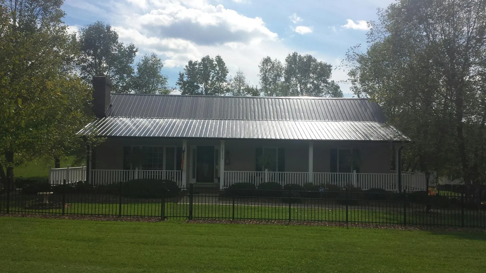 Gray metal roof on a brick ranch with a full width front porch — Gutter Guard Installation work by our crew in Skippack