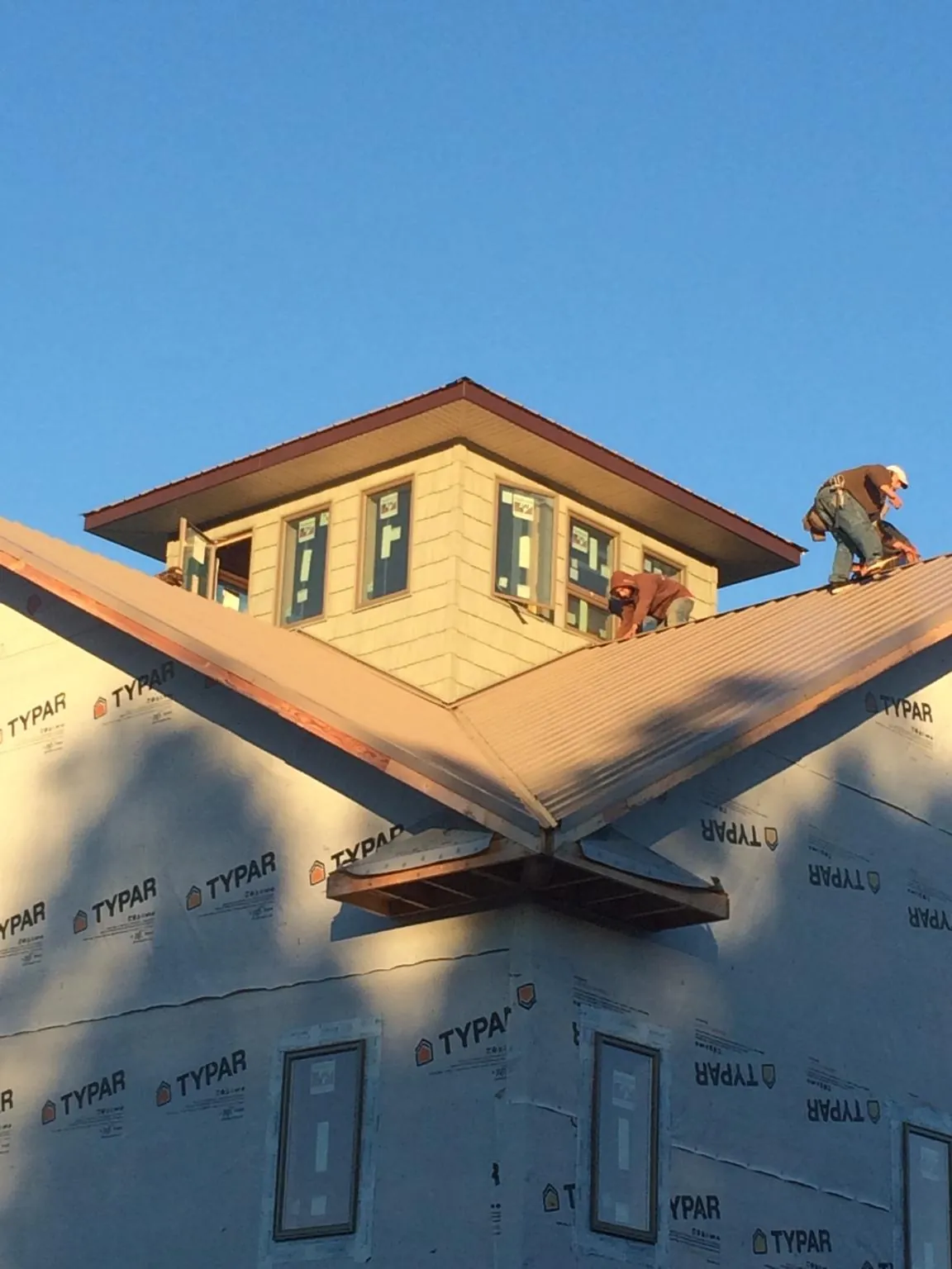 Roofers working around a rooftop cupola on a new metal roof at sunset — Roof Waterproofing in Skippack by Roofing Brothers